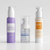 Three AROVANA skincare bottles arranged on a light gray studio background: a lavender Daily Brightening Gel Cleanser bottle on the left, a clear-topped Deep Hydration Hyaluronic Serum bottle in the center, and a white Hydrating Sun Shield SPF 60 PA++++ bottle on the right.